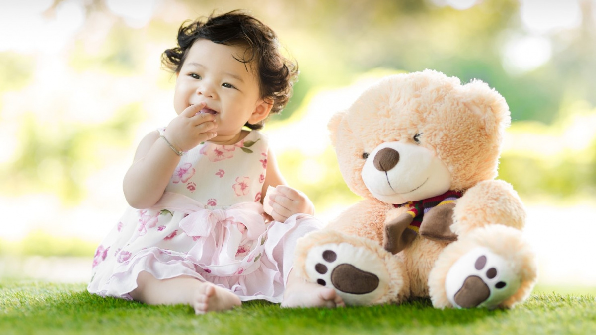 baby-sitting-on-green-grass-beside-bear-plush-toy-at-daytime-1166473.jpg